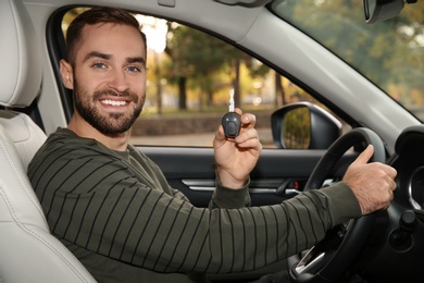 Young man holding car key in auto. Driving license test