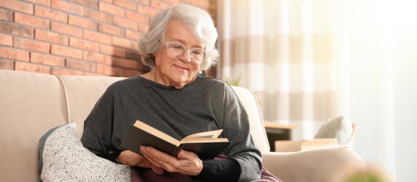 Elderly woman reading book on sofa in living room. Banner design