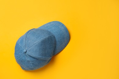 Baseball cap on orange background, top view. Space for text