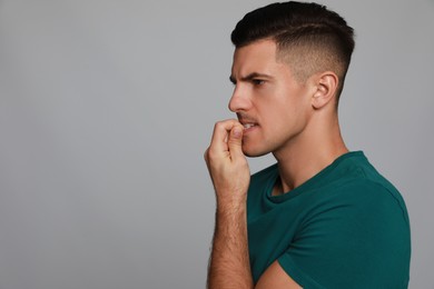 Photo of Man biting his nails on grey background, space for text. Bad habit