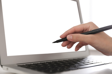 Woman pointing at modern laptop with blank screen, closeup