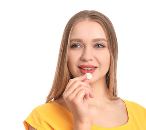 Young woman taking vitamin pill on white background