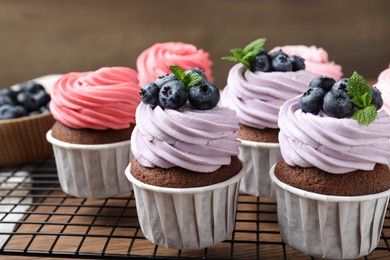 Sweet cupcakes with fresh blueberries on wooden table, closeup