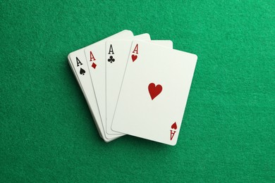 Four aces playing cards on green table, top view. Poker game