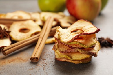 Delicious apple chips and cinnamon on grey table, closeup