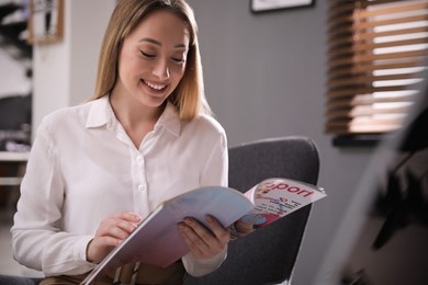 Happy woman reading interesting magazine in office