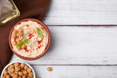 Delicious hummus with chickpeas and paprika served on white wooden table, flat lay. Space for text