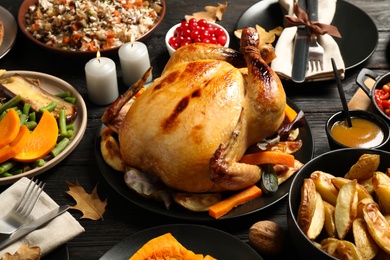 Traditional Thanksgiving day feast with delicious cooked turkey and other seasonal dishes served on black wooden table