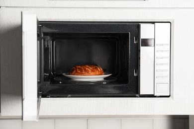 Photo of Open modern microwave oven with dessert in kitchen