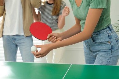 Photo of Woman playing ping pong with friends indoors, closeup
