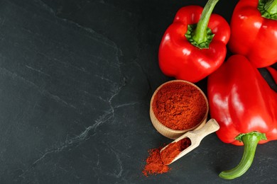 Paprika powder and fresh bell peppers on black table, above view. Space for text
