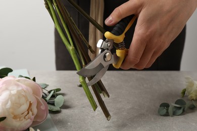 Florist cutting flower stems with pruner at workplace, closeup