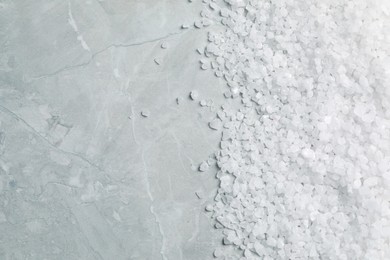 Natural sea salt on light grey marble table, top view. Space for text