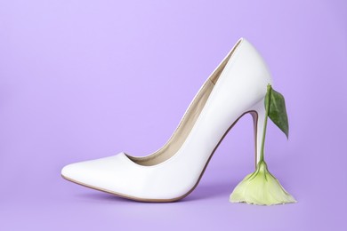 Stylish women's high heeled shoe with beautiful flower on violet background