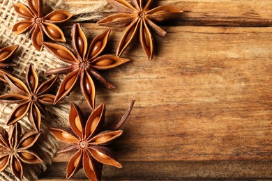 Aromatic anise stars on wooden table, flat lay. Space for text