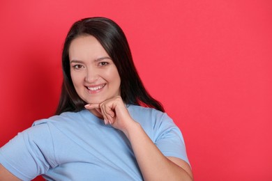 Beautiful overweight woman with charming smile on red background. Space for text