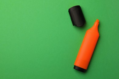 Photo of Bright orange marker on green background, flat lay. Space for text