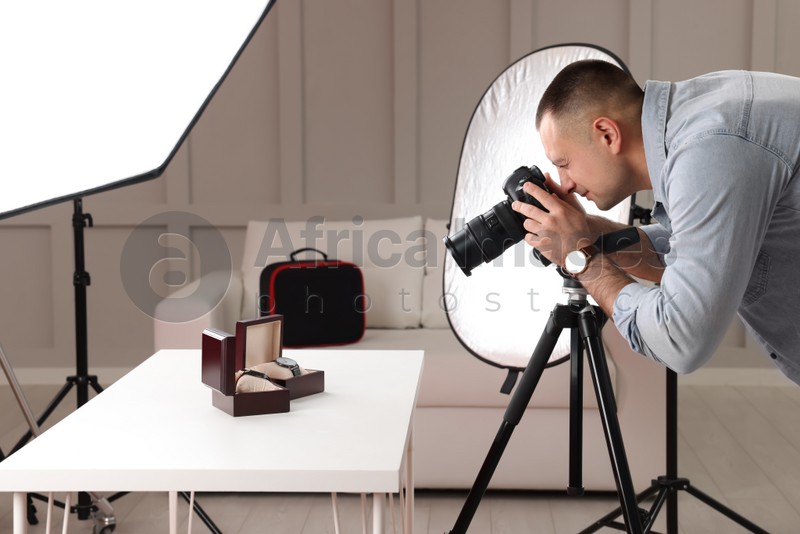 Photo of Professional photographer taking picture of expensive wristwatches in studio
