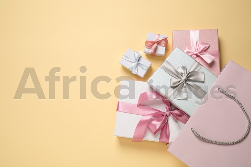 Paper bag with beautiful gift boxes on beige background, flat lay. Space for text
