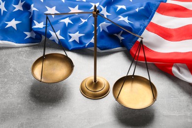 Scales of justice and American flag on light grey table