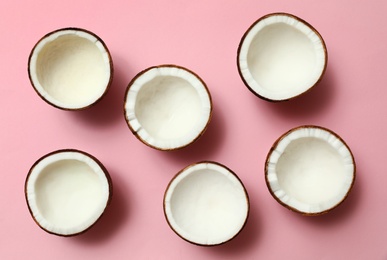 Fresh coconut halves on pink background, flat lay