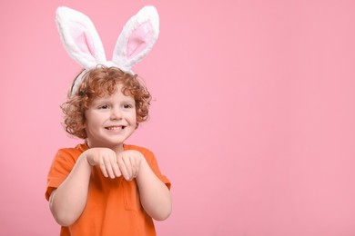 Photo of Happy boy wearing cute bunny ears headband on pink background, space for text. Easter celebration