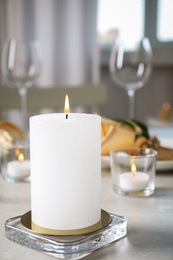 White burning wax candle on light table