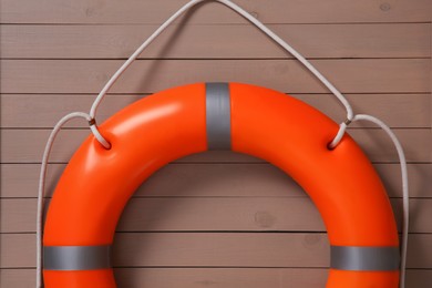 Orange lifebuoy on light brown wooden background. Rescue equipment