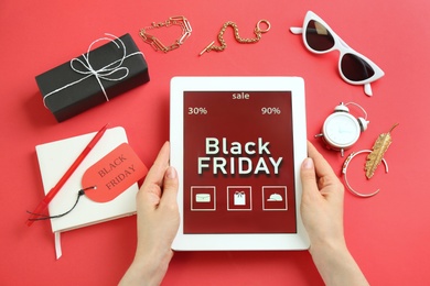 Woman with tablet surrounded by stylish accessories on red background, top view. Black Friday sale