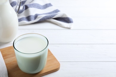 Glass of fresh milk on white wooden table. Space for text