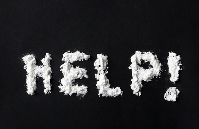 Text Help written with cocaine powder on black background, top view