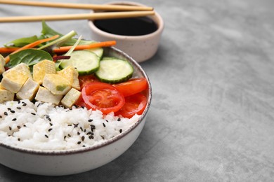 Photo of Delicious poke bowl with vegetables, tofu and mesclun served on light grey table, closeup. Space for text