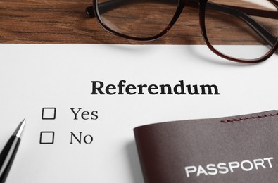 Referendum ballot with pen, passport and glasses on wooden table, closeup