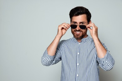 Photo of Portrait of smiling bearded man with sunglasses on grey background. Space for text