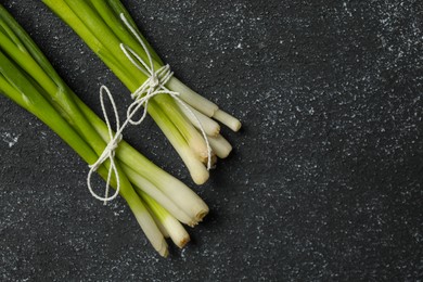 Bunch of fresh green onion on black table, flat lay. Space for text