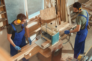 Professional carpenters working together in shop, view from above