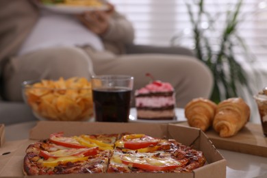Overweight man at home, focus on pizza