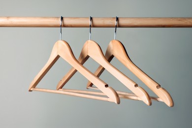 Clothes hangers on wooden rail against beige background