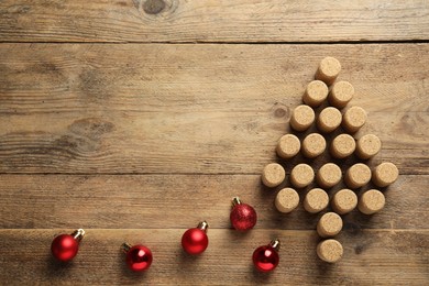 Photo of Christmas tree made of wine corks and baubles on wooden table, top view