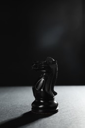 Black knight on table against dark background, space for text. Chess piece