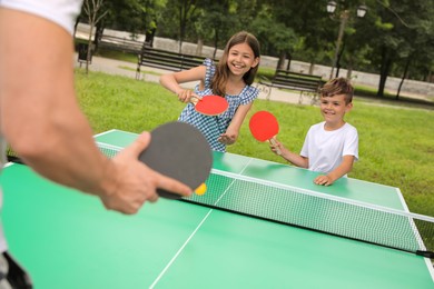 Man with children playing ping pong in park