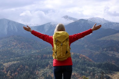 Happy woman with backpack admiring mountain landscape, back view. Feeling freedom