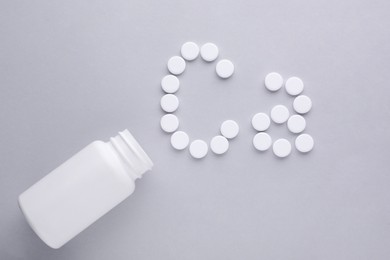 Open bottle and calcium symbol made of white pills on light grey background, flat lay