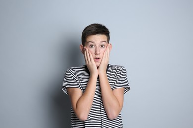 Portrait of surprised teenage boy on grey background