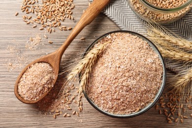 Photo of Wheat bran, kernels and spikelets on wooden table, flat lay