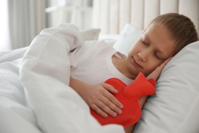 Ill boy with hot water bottle suffering from cold in bed at home