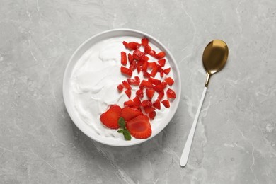 Delicious yogurt with strawberries served on grey marble table, top view