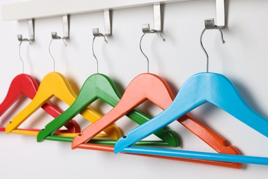 Photo of Rack with empty bright clothes hangers on white wall