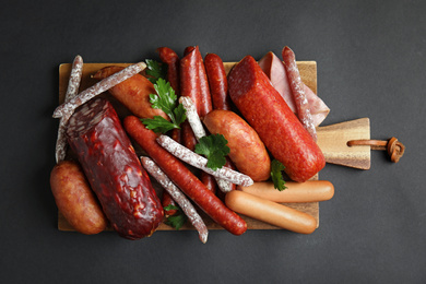 Different types of sausages served on black background, top view