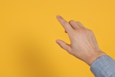 Man pointing at something against yellow background, closeup on hand. Space for text